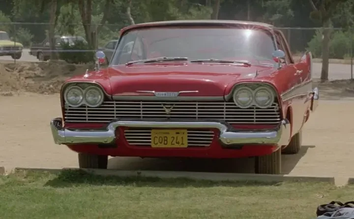 Um carro modelo Plymouth Fury 1958, estacionado na frente de um gramado.