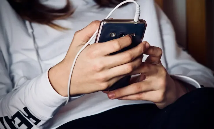 Uma mulher deitada com um celular na mão.