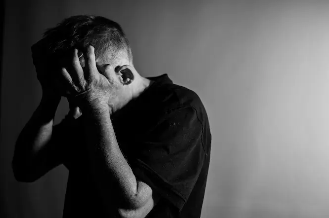 Um homem de meia idade desesperado, com as mãos na cabeça.
